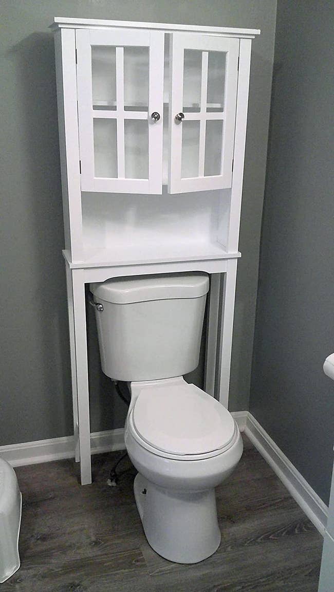 a reviewer photo of the white cabinet above a toilet