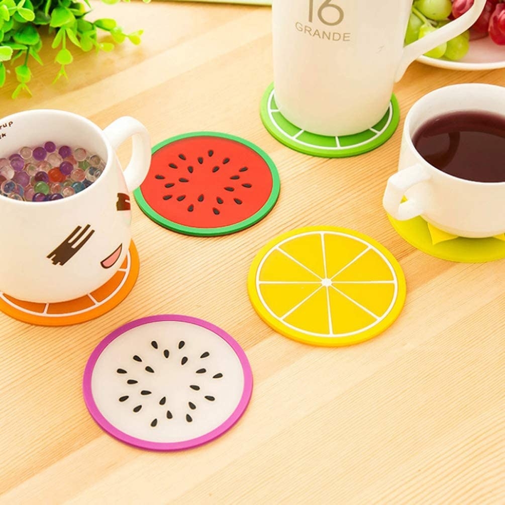 The coasters in various fruit styles, some with mugs sitting on them