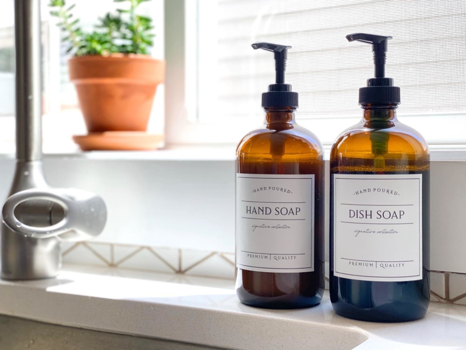 two refillable hand soap bottles on side of kitchen sink