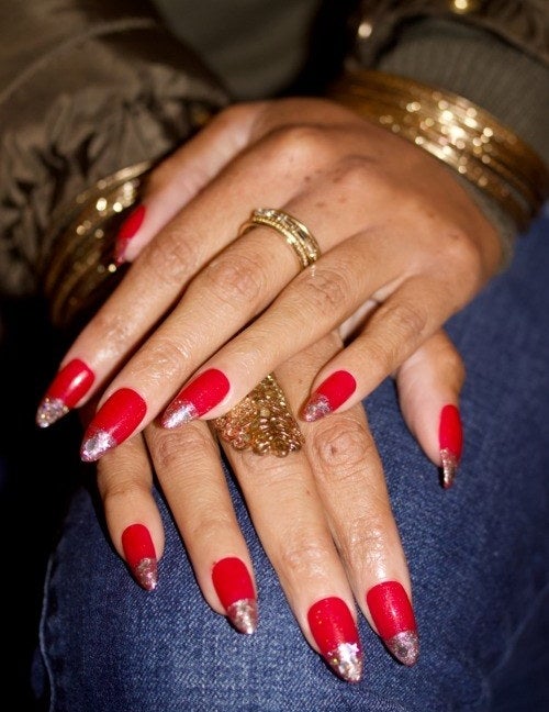 Model wearing red nails topped with gray glitter, placing their hands on denim jeans.