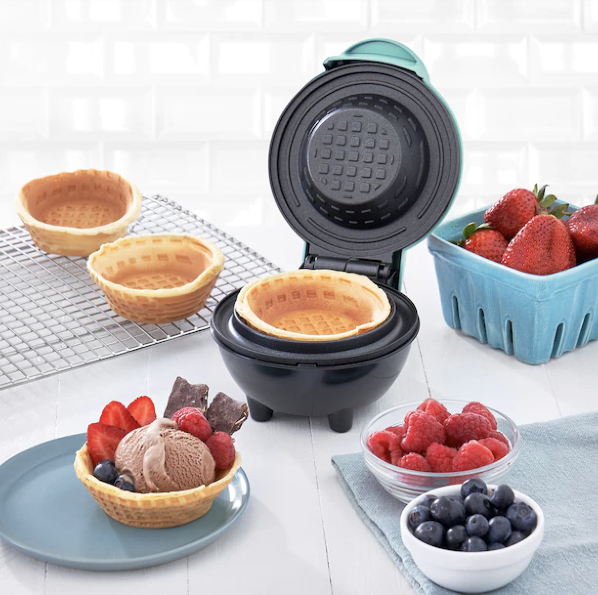 the waffle bowl maker with the waffle in it surrounded by berries