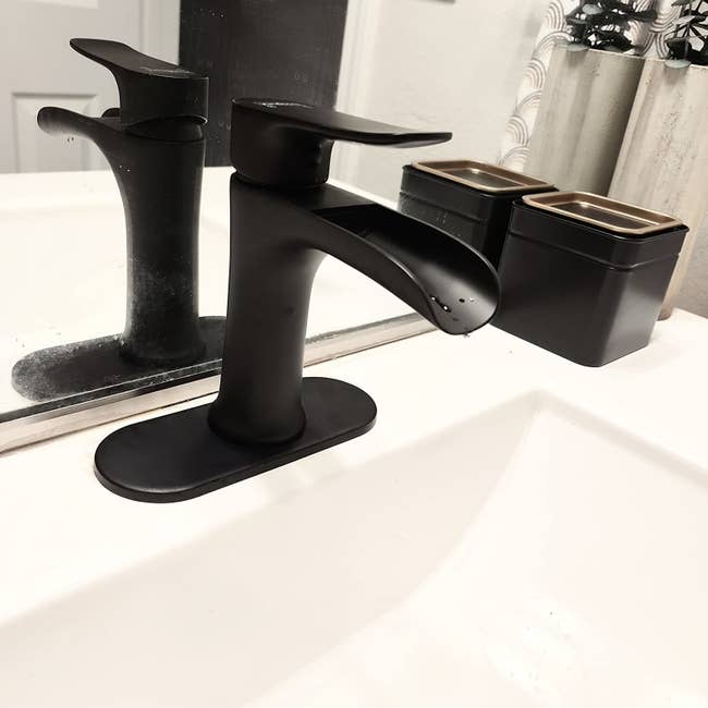 a reviewer photo of the black faucet installed in a decorated white sink area