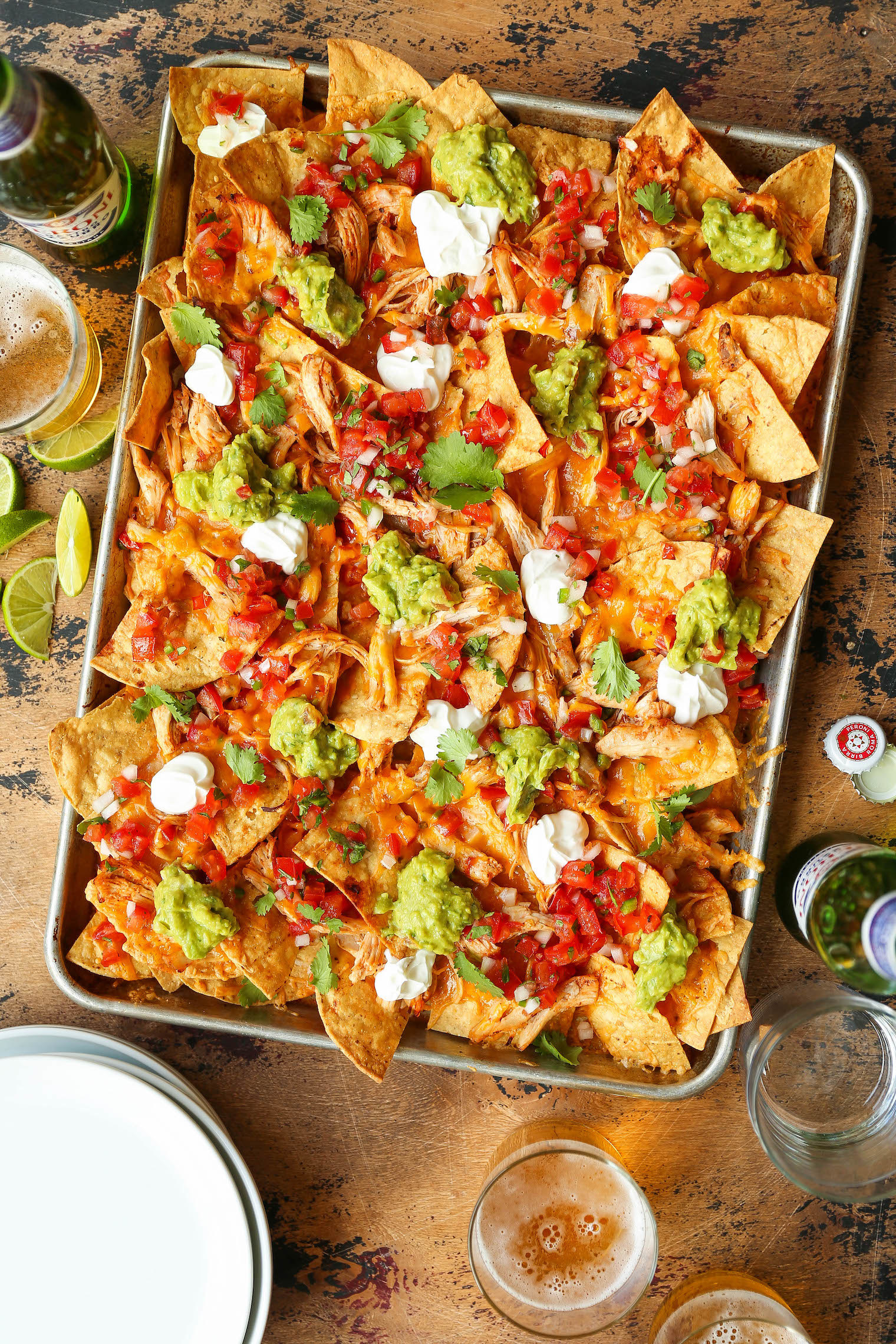 Tray of nachos topped with guacamole, sour cream and chicken