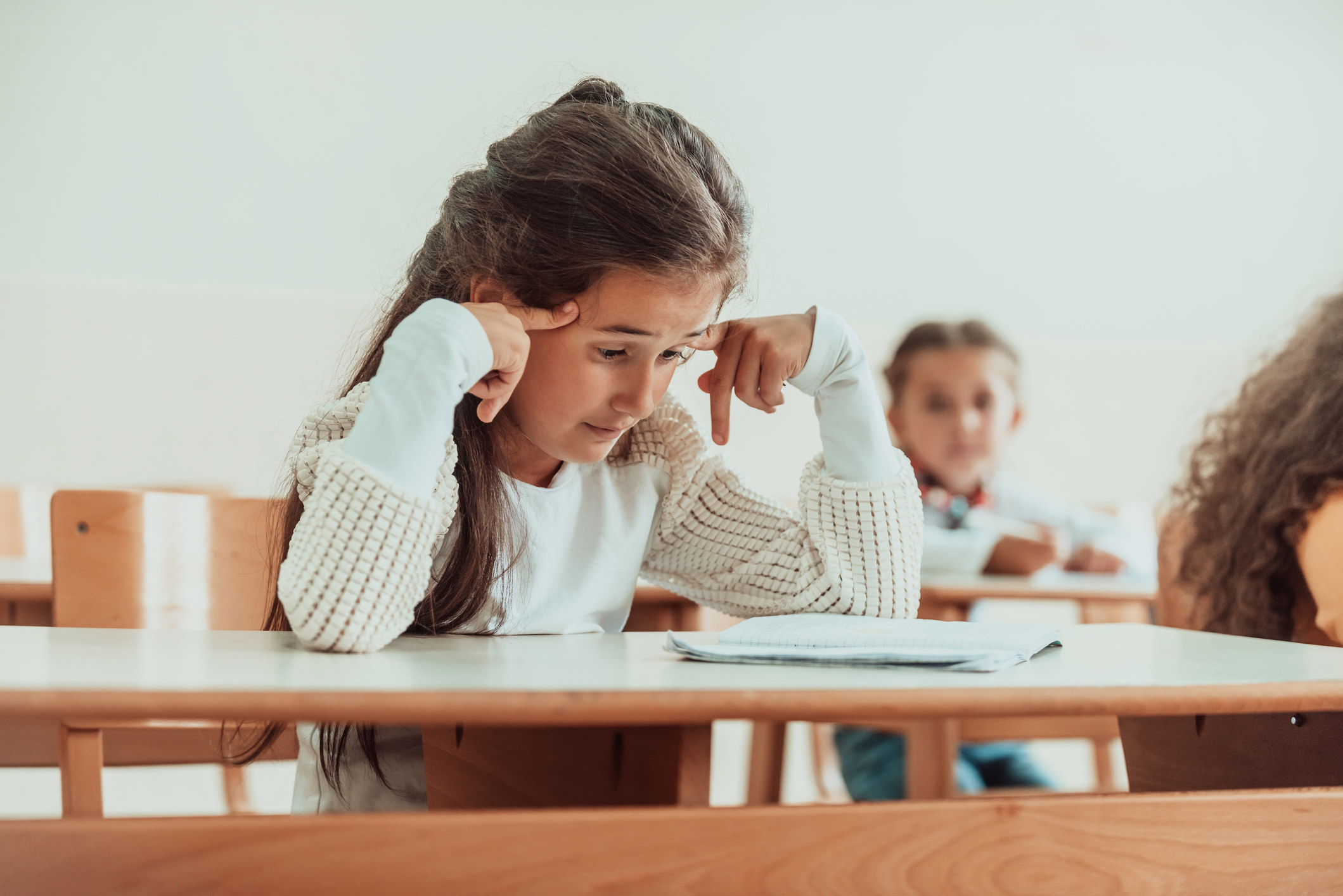 Child sitting at a desk looking down at a piece of paper