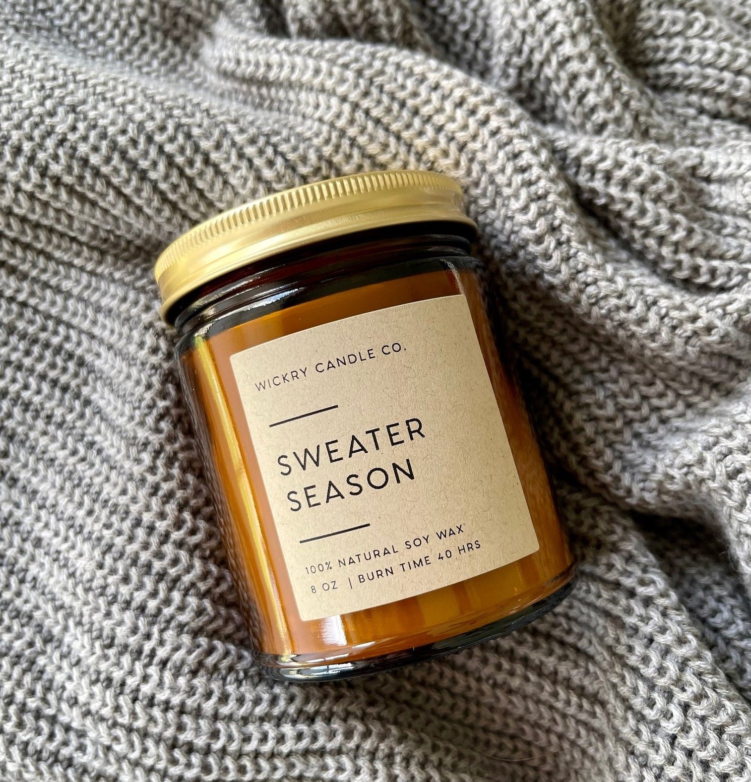 amber sweater weather candle in a glass jar with a gold screw-top lid