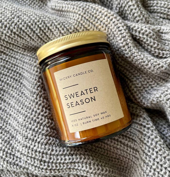amber sweater weather candle in a glass jar with a gold screw-top lid