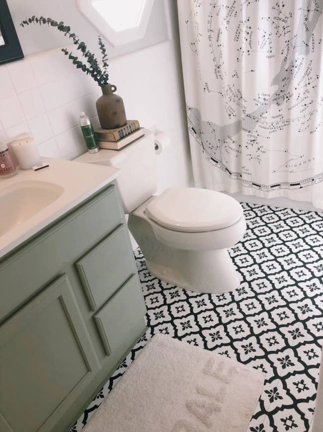 a reviewer photo of their bathroom with the black and white patterned floor tiles
