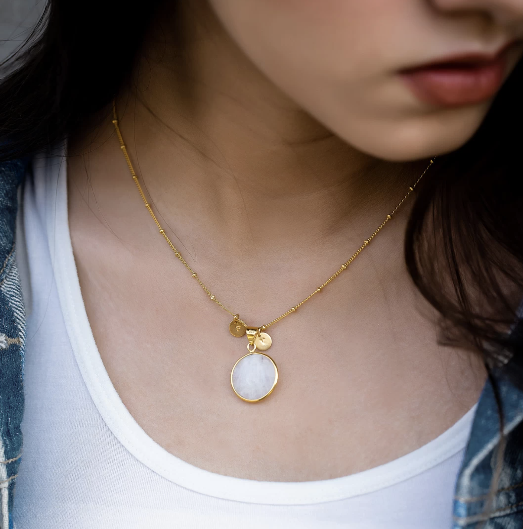 Model wearing customized gold necklace with moonstone attached.