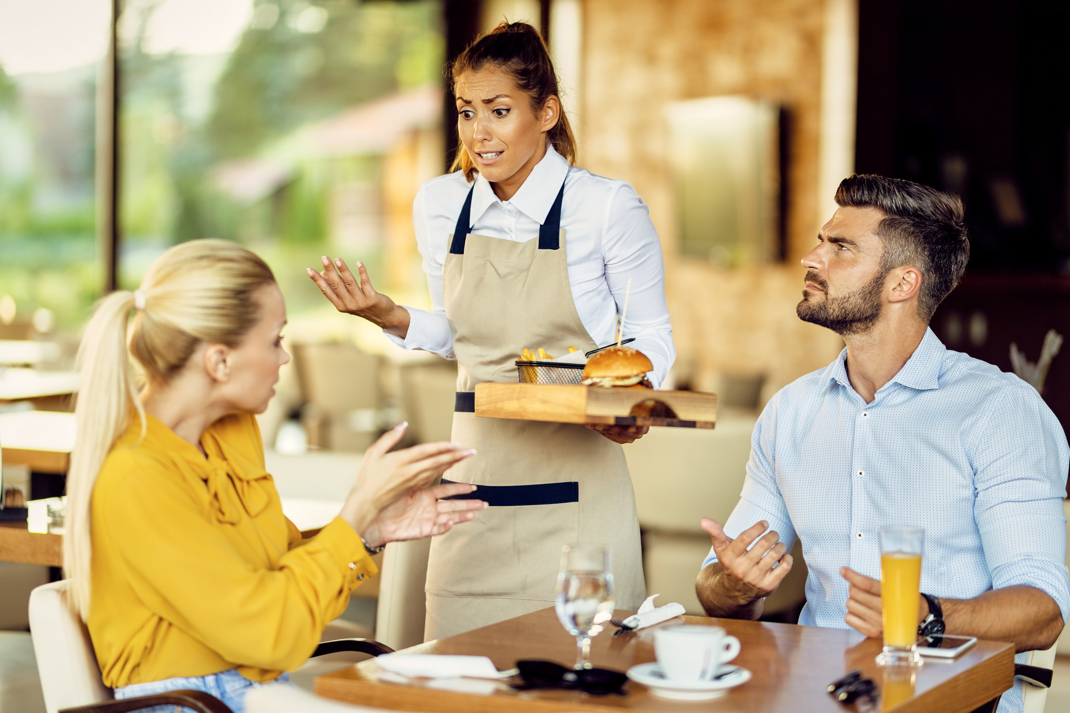 couple aggressively speaking to a server who looks sorry