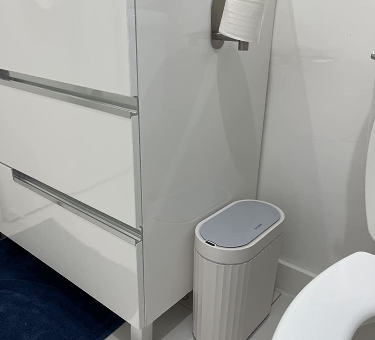 a reviewer photo of the small white trash can in a white bathroom