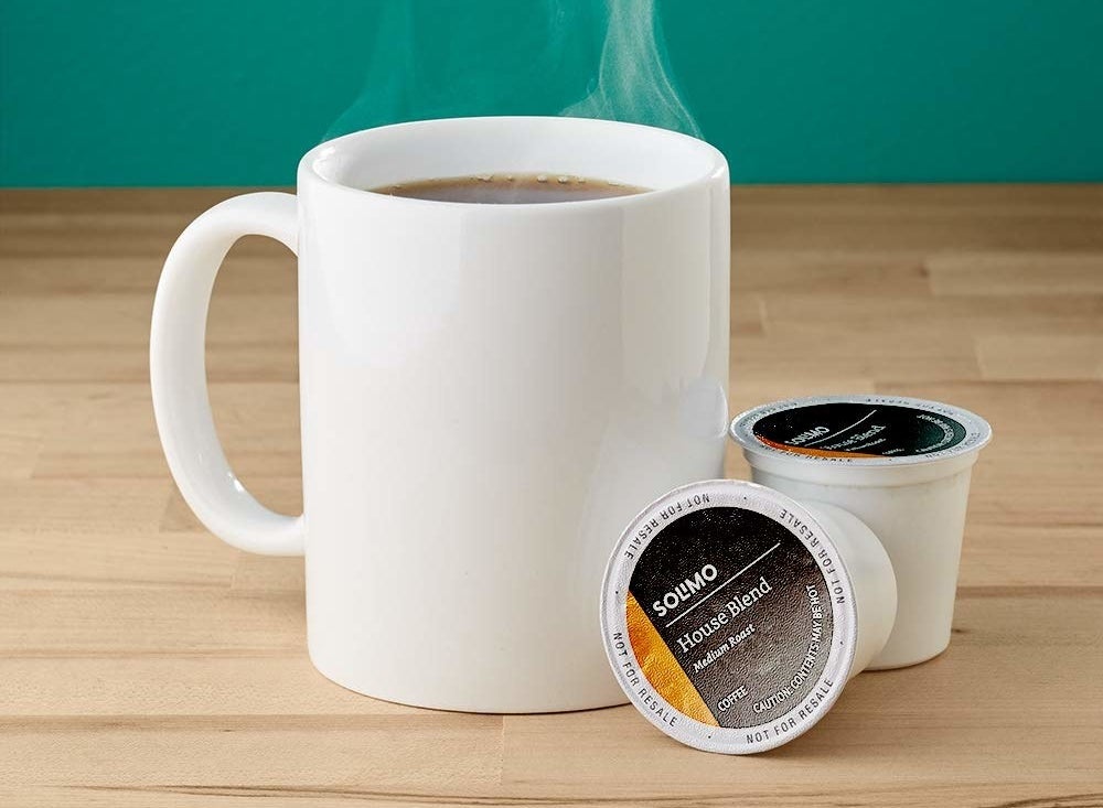 mug of coffee next to two house blend coffee pods