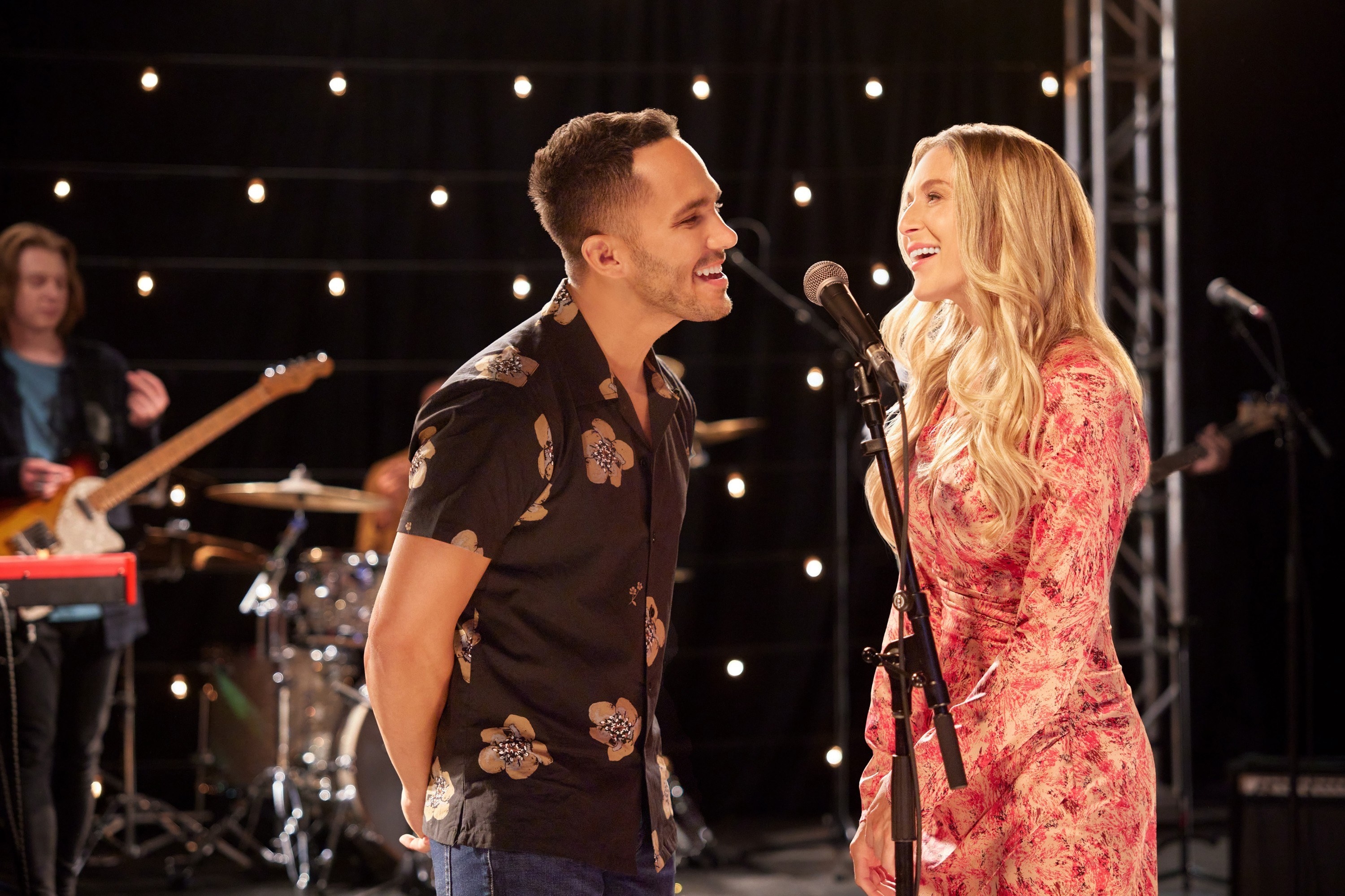 Carlos and Alexa onstage at a microphone together