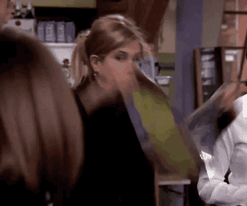 GIF of Jennifer Aniston on Friends holding up banner that says, &quot;Bon Voyage&quot;