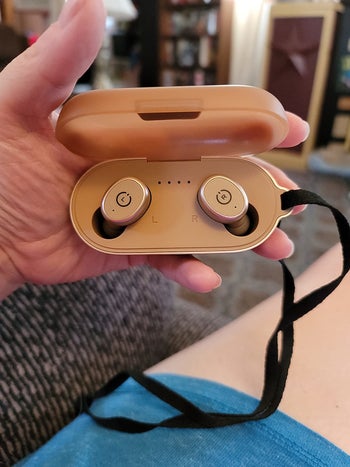 Reviewer holding the golden headphones in the case