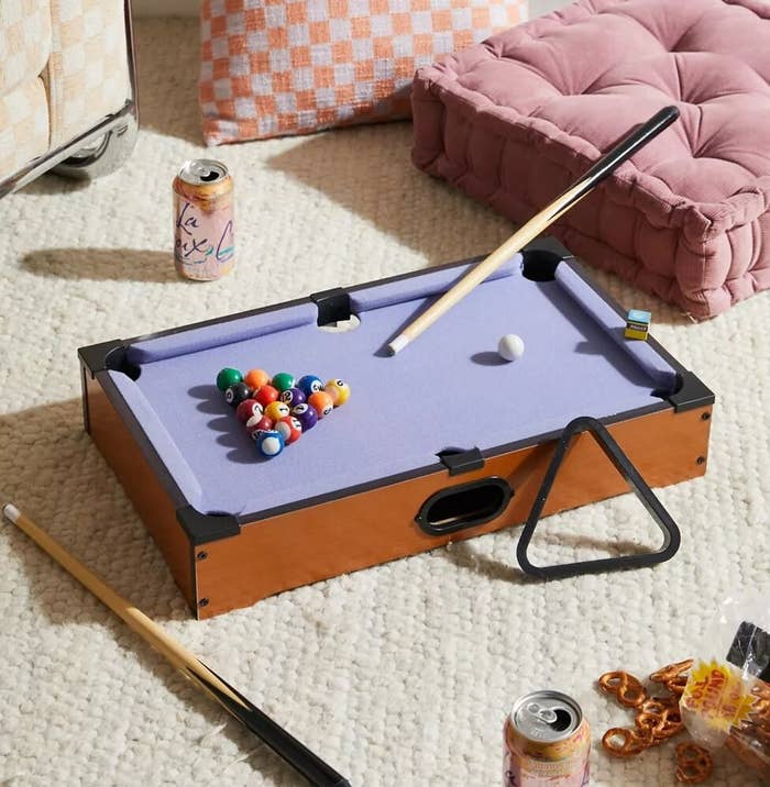 the pool table on carpet next to cushions and snacks