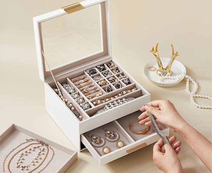 the jewellery box filled with jewellery and someone touching a bracelet