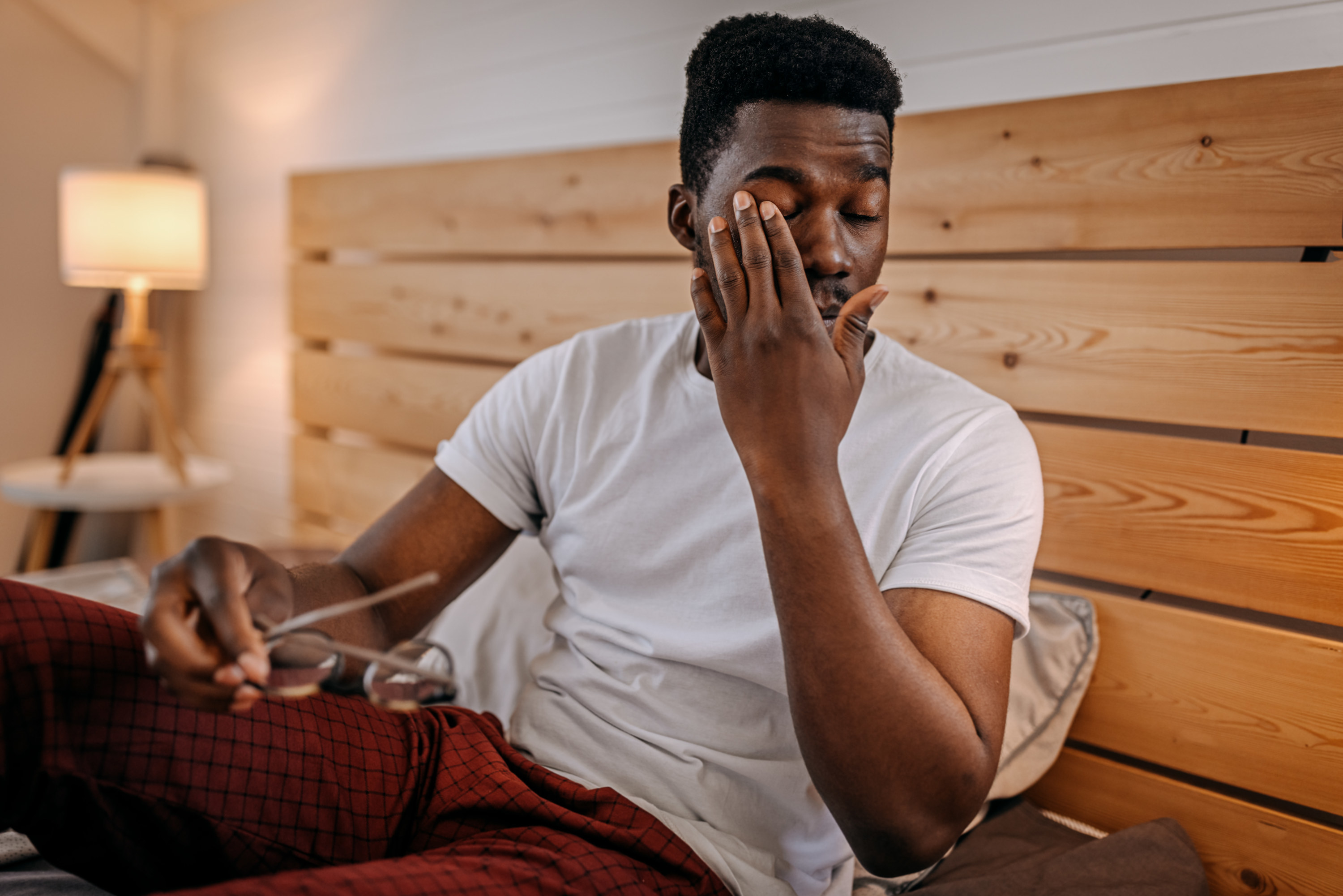 a man rubbing his eye while in bed