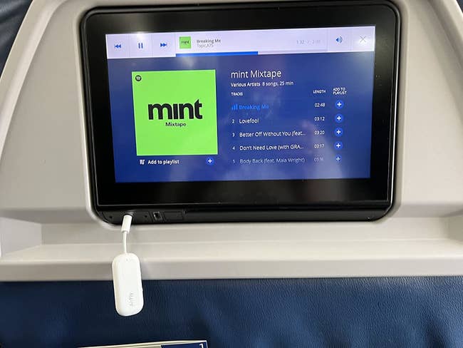 the white converter plugged into the headphone jack on an airplane seat screen