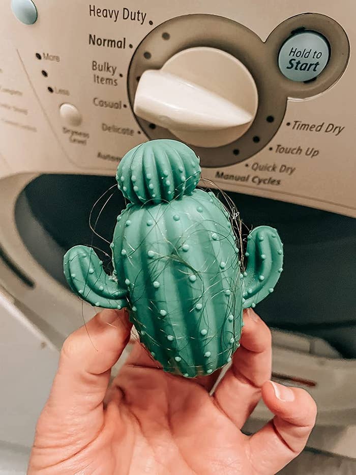 The green dryer balls in a reviewer&#x27;s hand, with hair wrapped around it