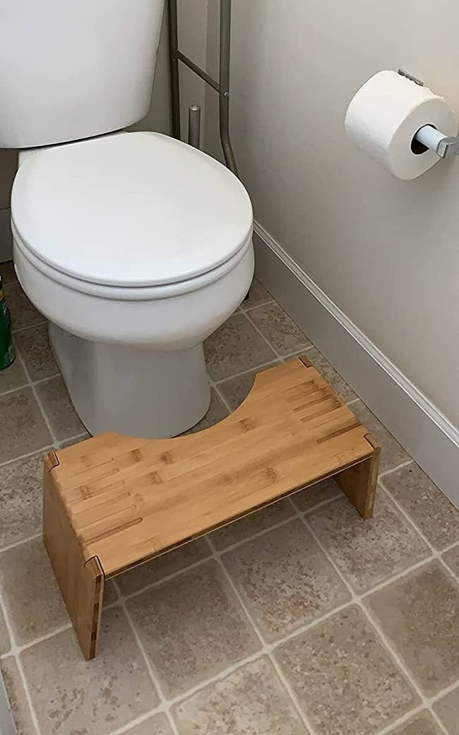 a reviewer photo of the light wood stool in front of a toilet