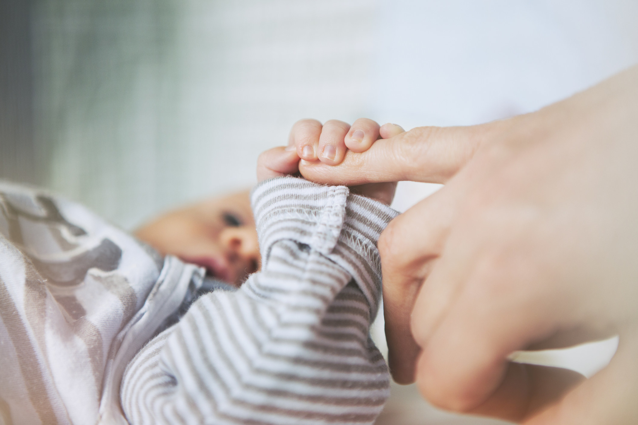 A mother holding a newborn&#x27;s hand.