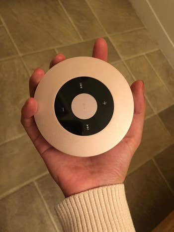 The small round pink metallic speaker in a reviewer's hand