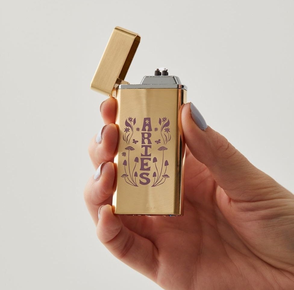 The gold lighter with &quot;aries&quot; on the front in lavender with mushrooms around it