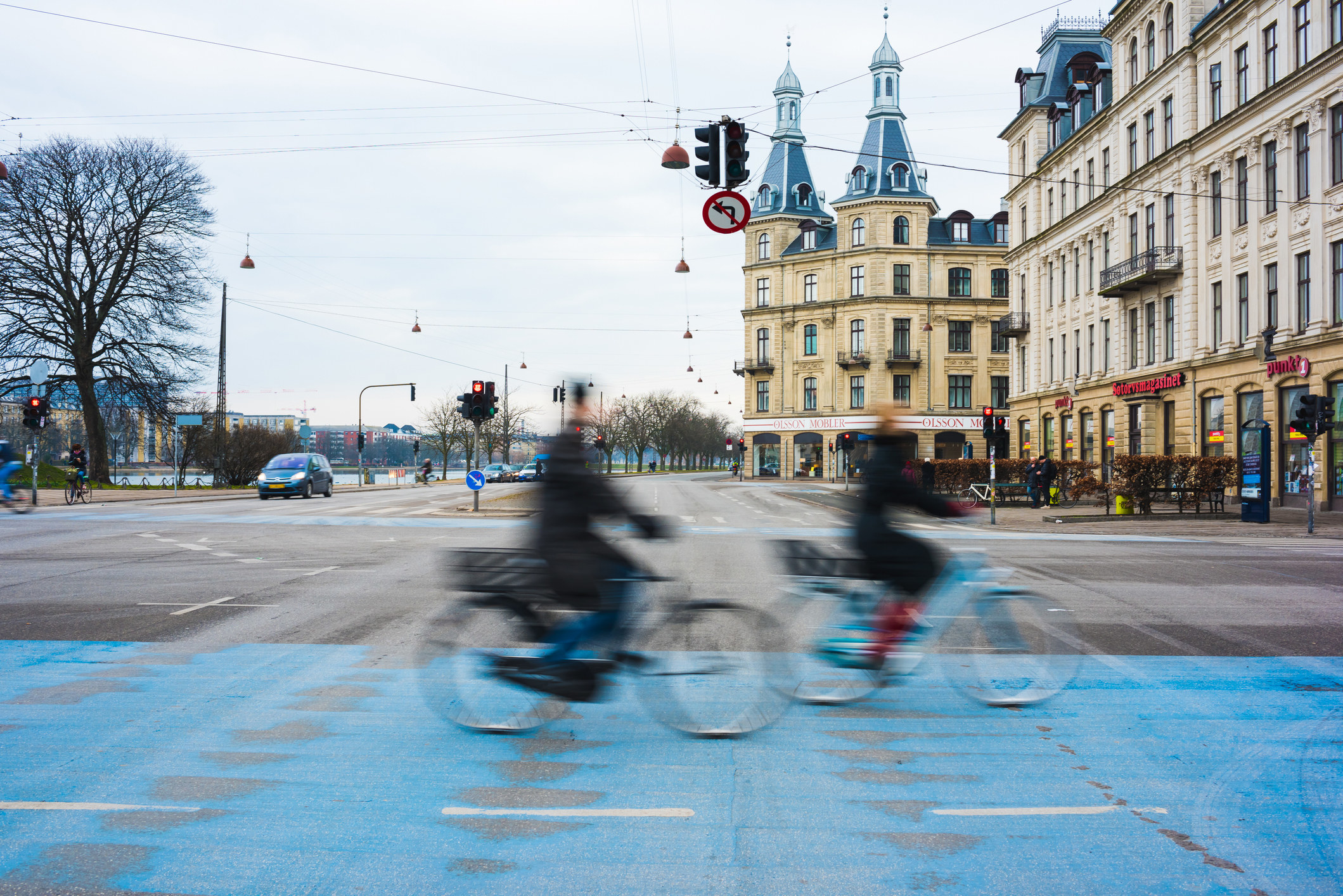 Two cyclists speeding along blue city cycle path