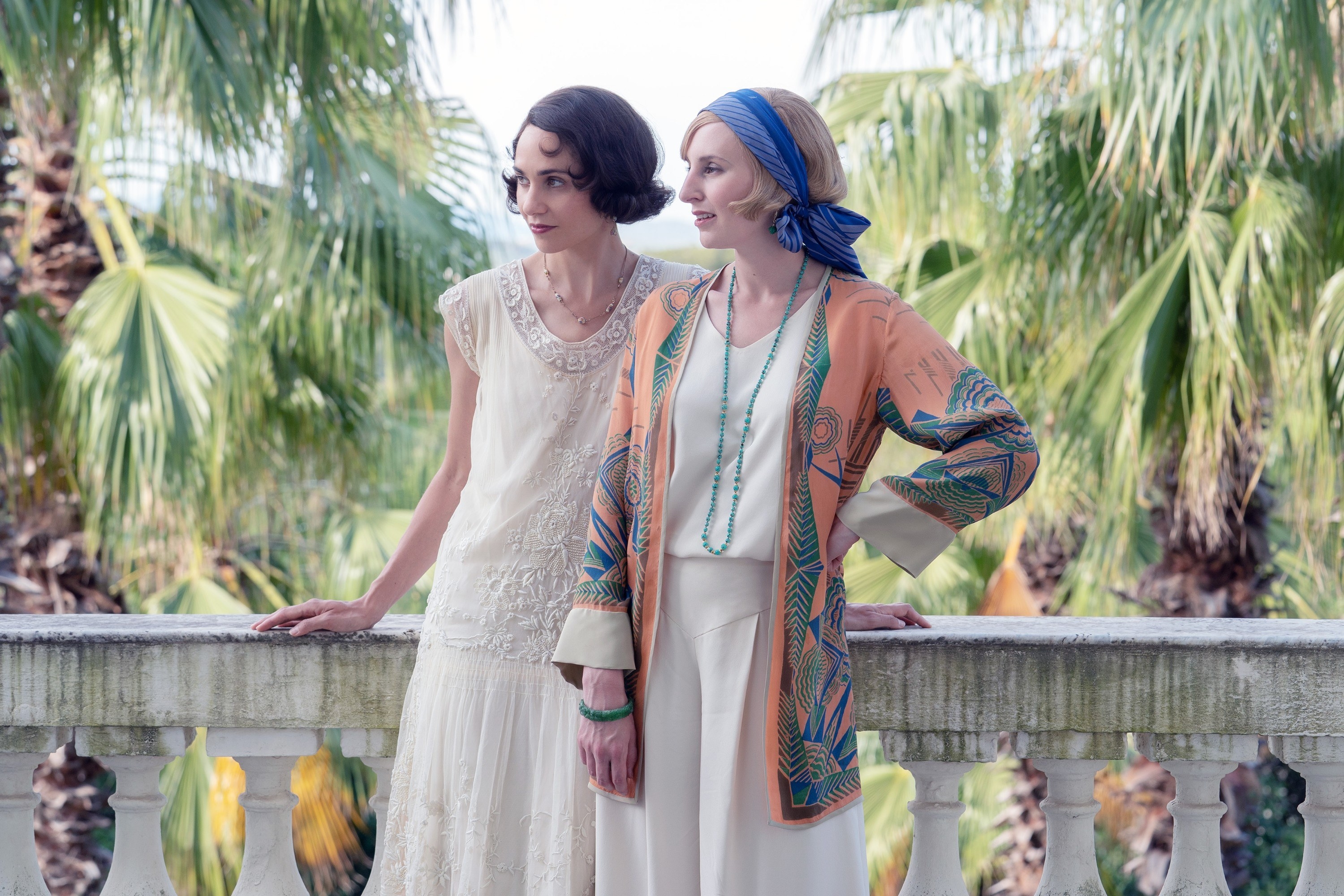 Tuppence Middleton and Laura Carmichael stand outside on a villa balcony in Downton Abbey: A New Era.
