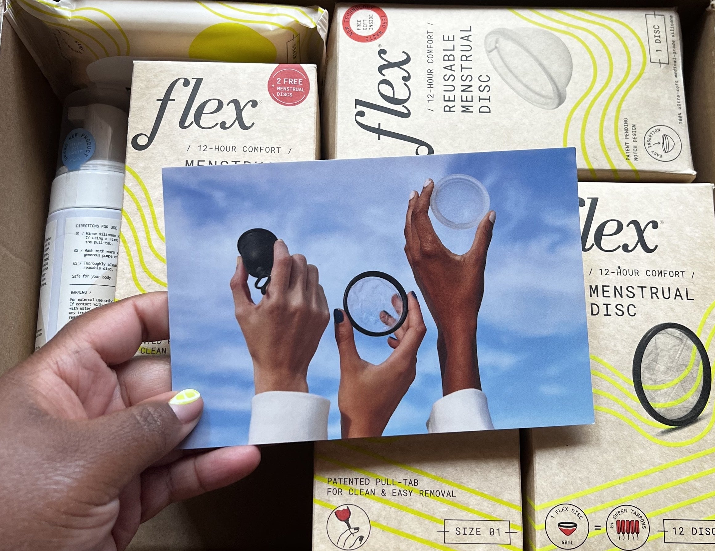 Hand holding flyer in front of box of Flex period products