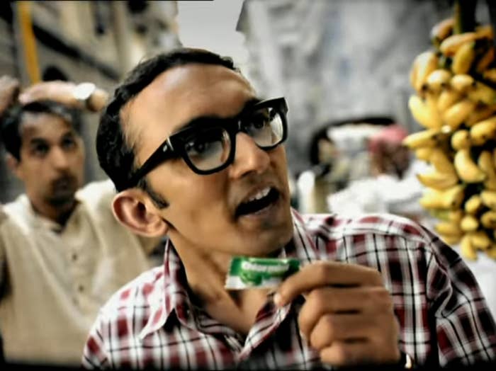 A man wearing spectacles holding a candy