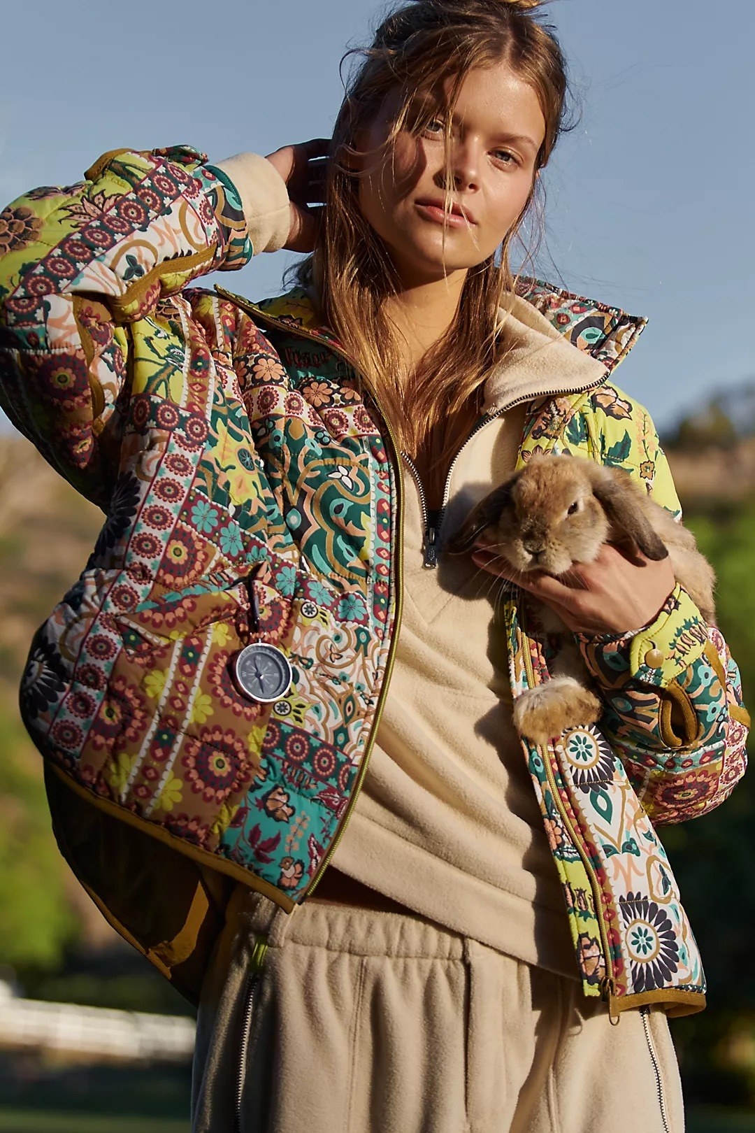 a model wearing the colorful patterned jacket while holding a rabbit