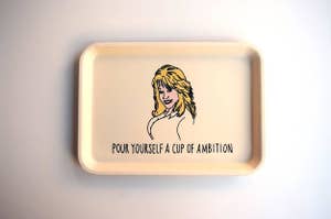 The beige tray with an illustration of Dolly and text "Pour yourself a cup of ambition"