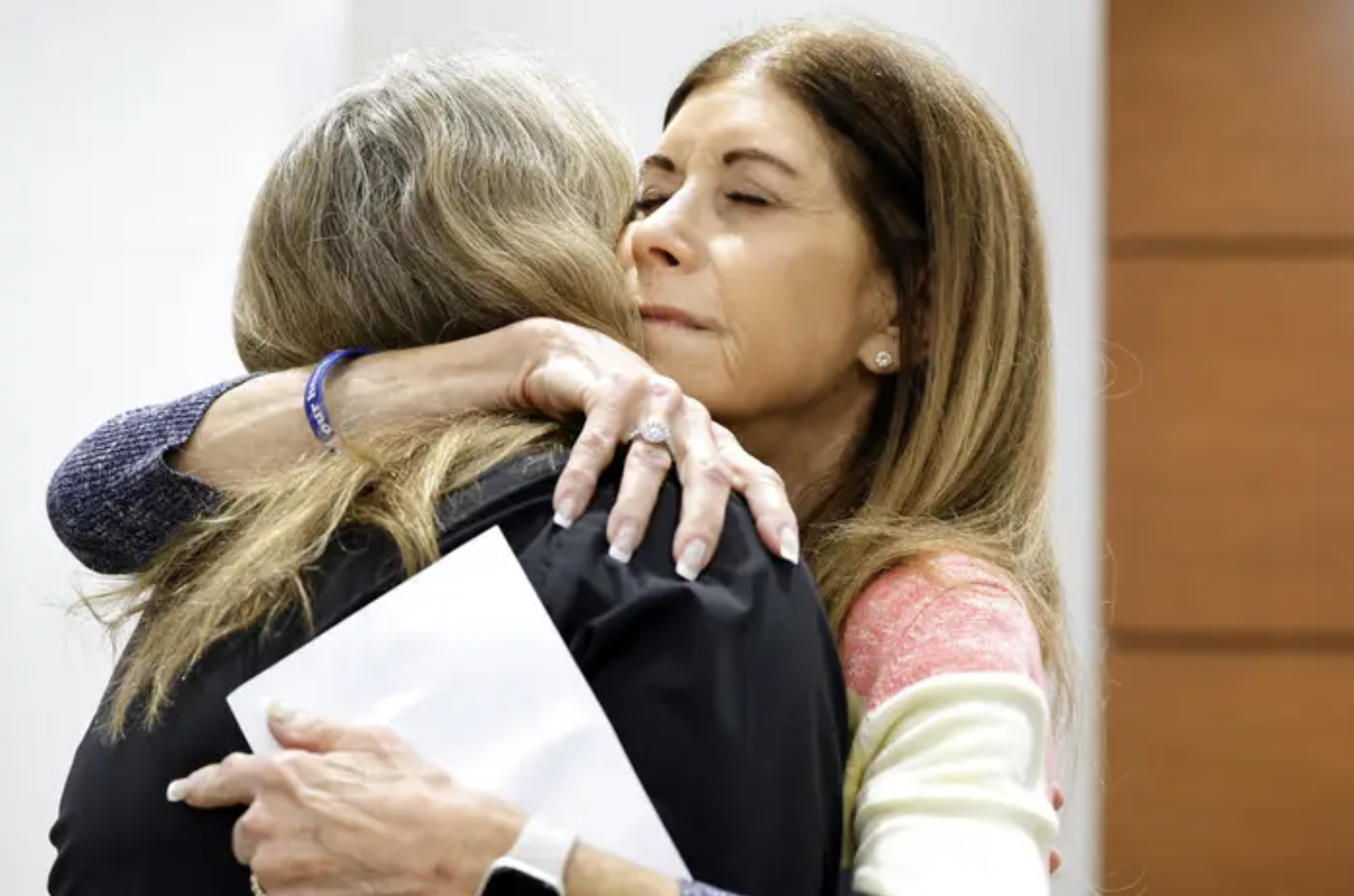 two women embrace in a court room