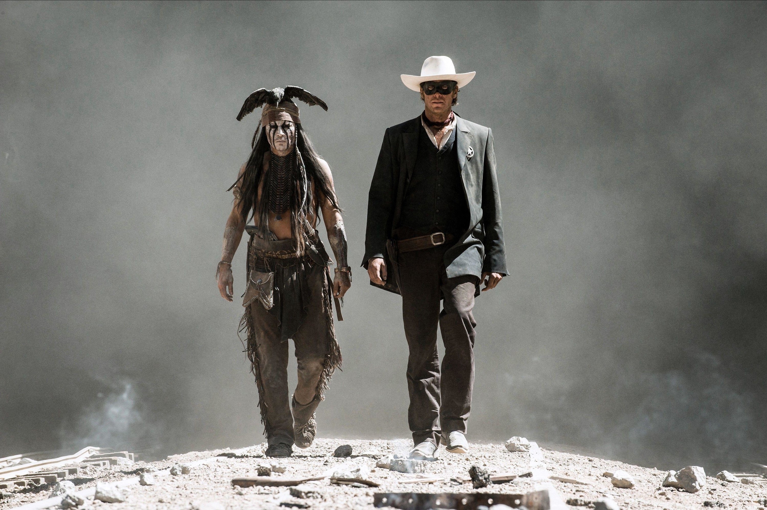 A Native American and a Cowboy walk out of a smoky background