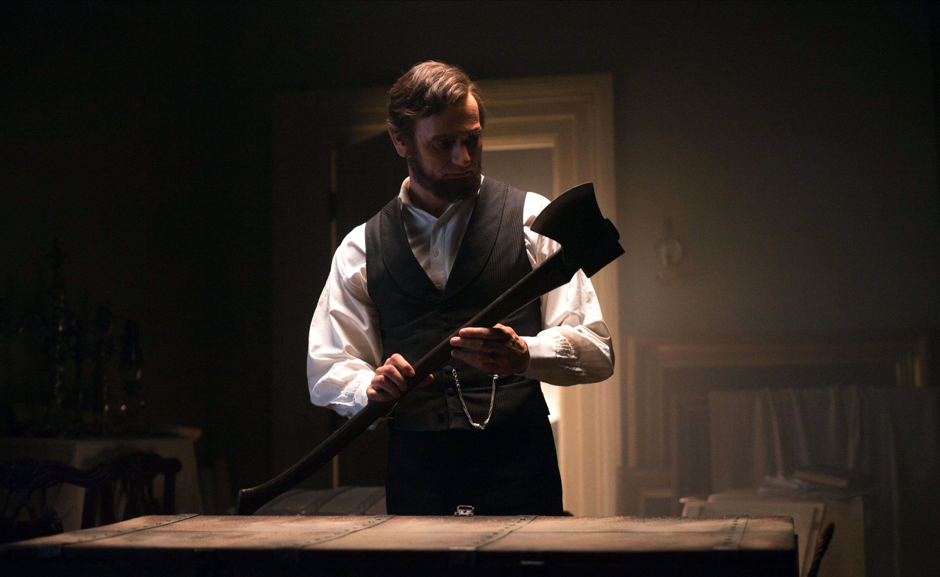 Abraham Lincoln examines an ax in a dark room