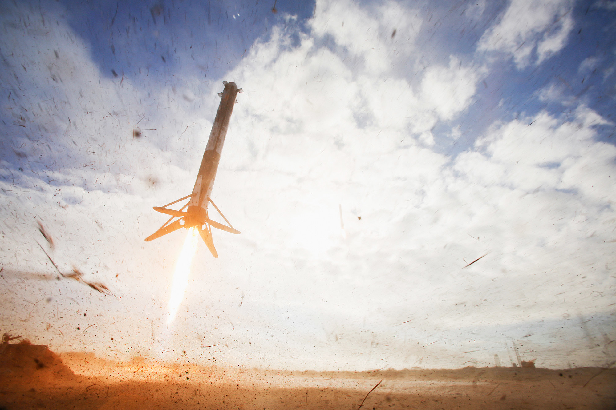 a rocket launches off the dirt into a clear blue sky