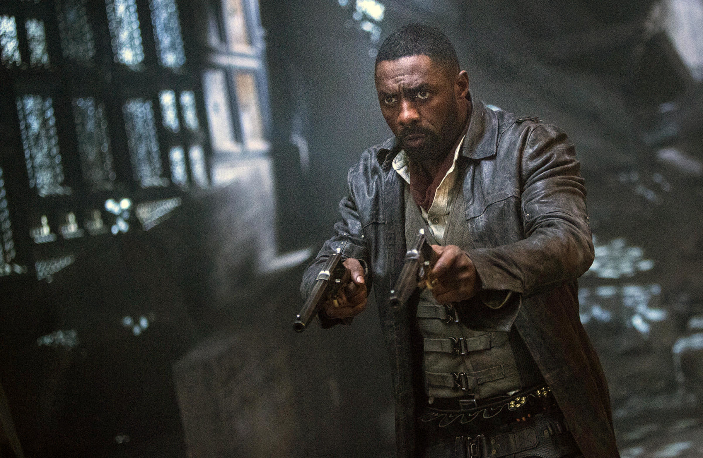 A man in a leather jacket holds two guns in some kind of ornate temple