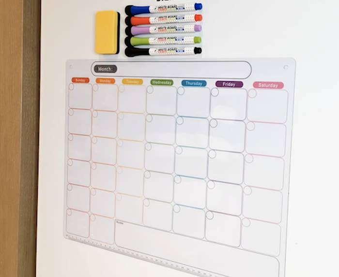 the calendar on a fridge with the included markers above it