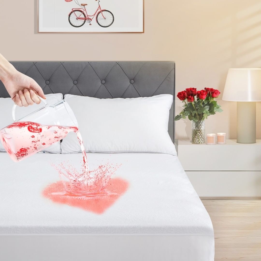 a person pouring liquid onto the mattress protector