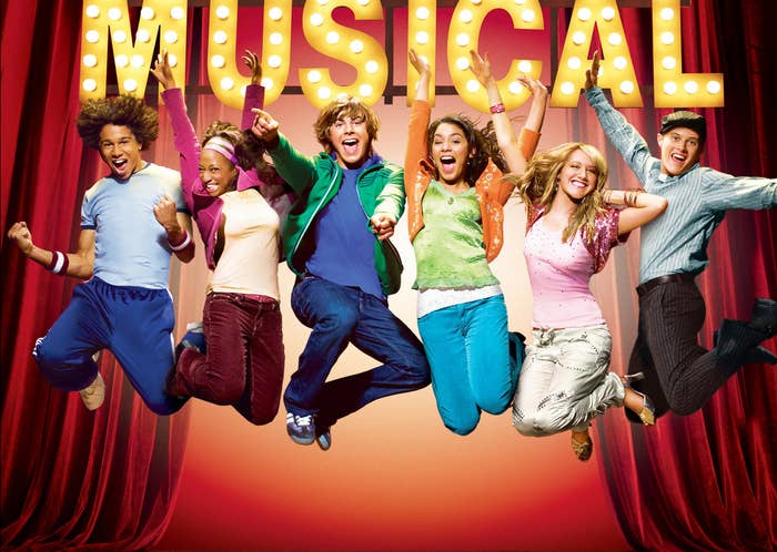 The high school musical cast jumps together on a stage
