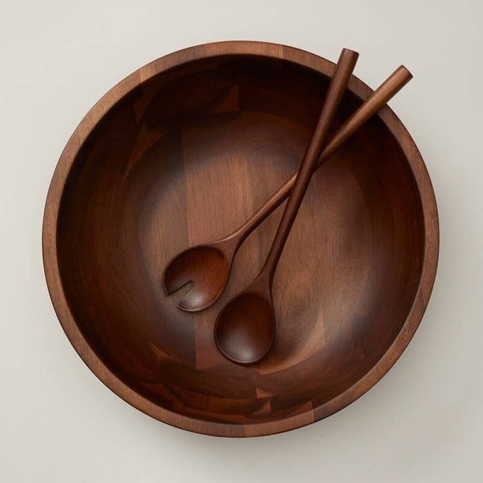 two wood salad servers in a matching bowl