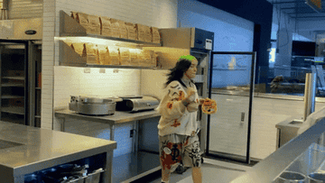 Billie Eilish jumping over a counter with pretzels