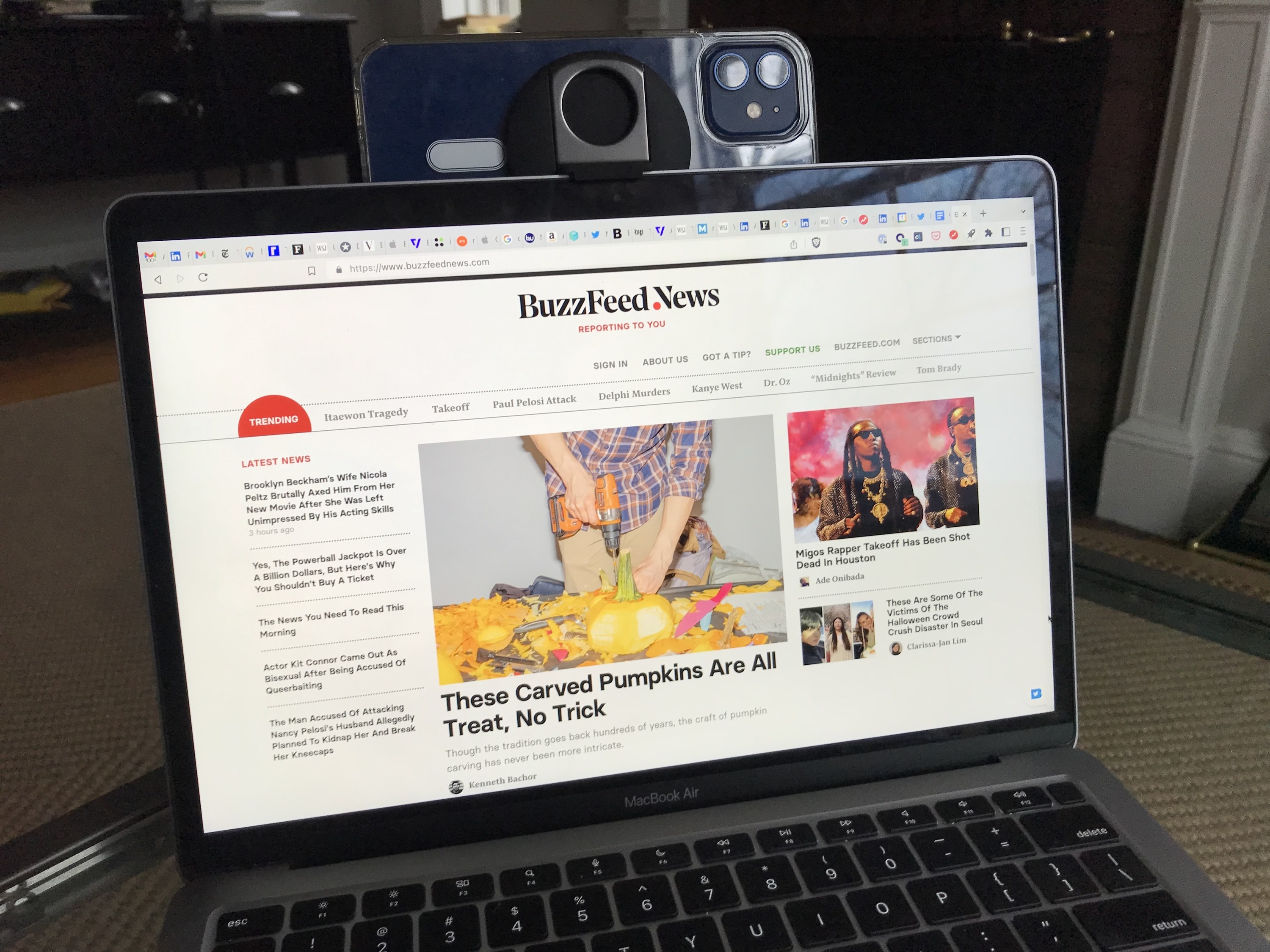 A phone attached to the author&#x27;s laptop with the BuzzFeed News homepage and about forty tabs opened