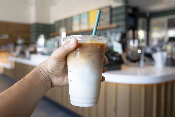 A person holding up an iced coffee drink