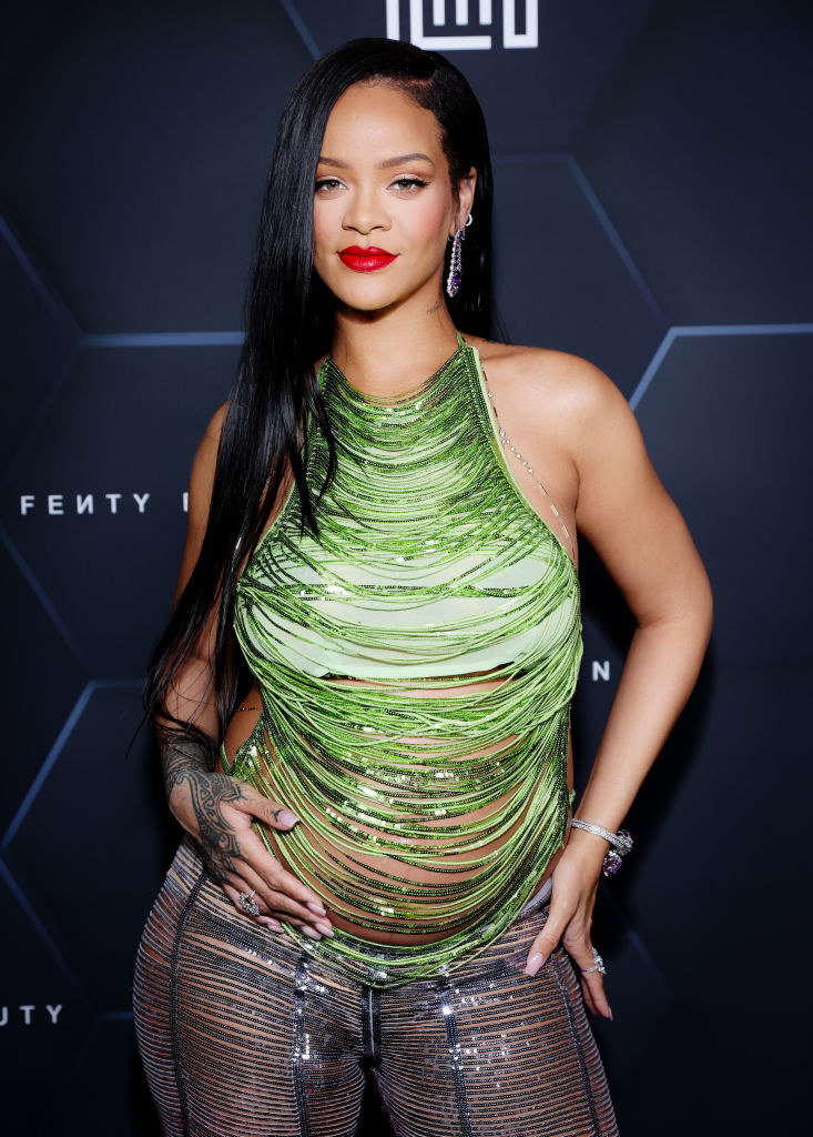Rihanna smiling with her hands on her hips