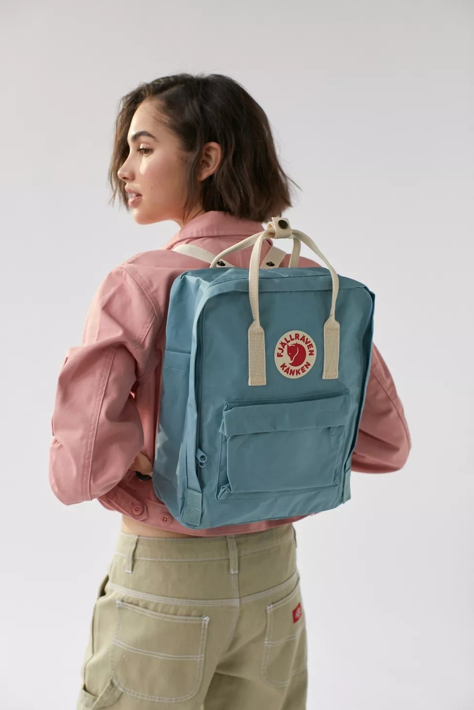 Model with the rectangle-shaped backpack with top handles, and a big front zippered pocket in blue
