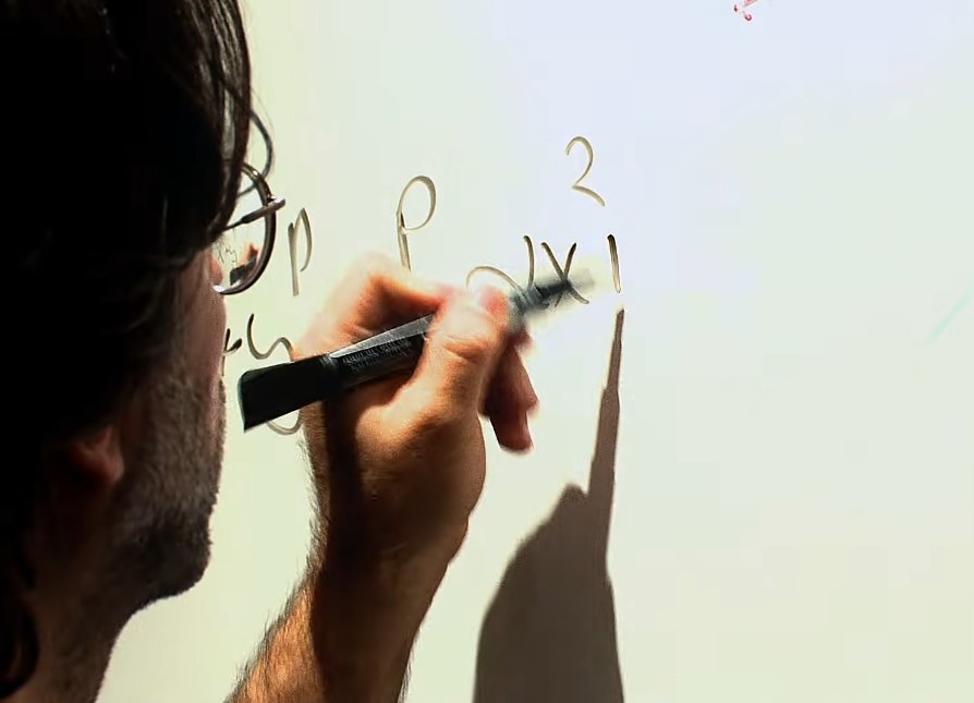 Keith Raniere writing on a white board