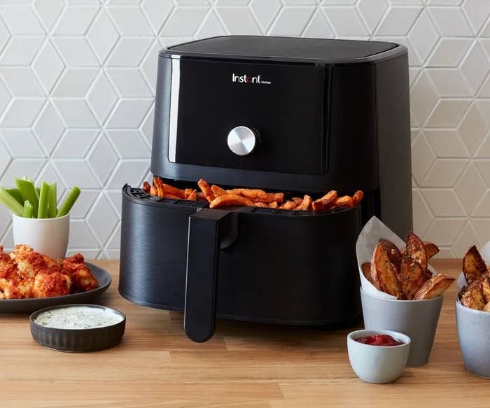 Air fryer in kitchen surrounded by food