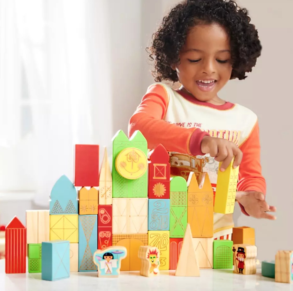 child playing with the small world block set, which looks like the outside of the Disney ride